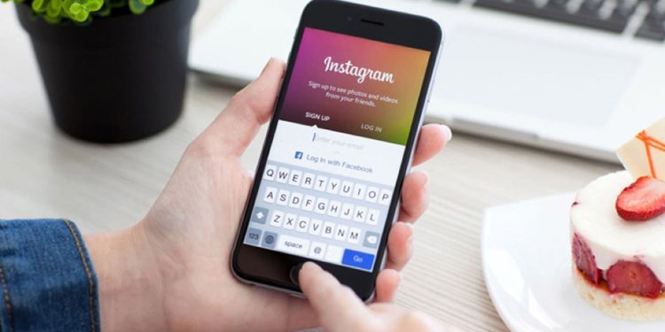 a man holding a phone looking at his instagram account
